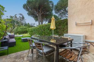 a table with chairs and an umbrella on a patio at Studio Saint Clair pieds dans l'eau in Le Lavandou