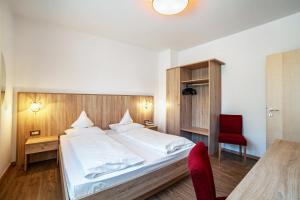 a bedroom with a large bed and a red chair at Gartenheim App Franz in Schenna