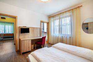 a bedroom with a bed and a desk with a computer at Gartenheim App Franz in Schenna