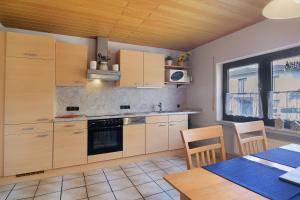 a kitchen with wooden cabinets and a table and a dining room at Eifelferienhaus Thome Lissendorf in Lissendorf