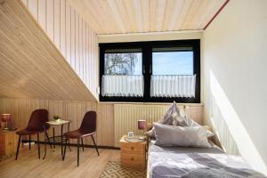 a bedroom with a bed and two chairs and a window at Eifelferienhaus Thome Lissendorf in Lissendorf