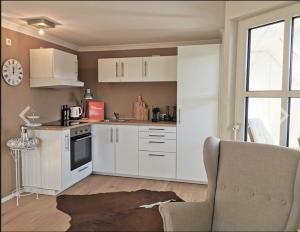 a kitchen with white cabinets and a chair in a room at Apartment Blackforest-Schluchsee in Schluchsee