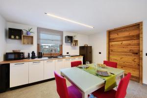 a kitchen with a table and red chairs in a kitchen at La Pièce de Leo in Châtillon