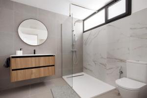 a bathroom with a shower and a toilet and a mirror at Las Cuestitas Sol in Pájara +17 photos