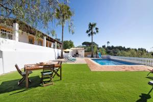 a garden with a table and chairs and a swimming pool at Casa Noah in São Bartolomeu de Messines