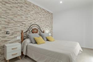 a bedroom with a bed and a brick wall at Casa Unifamiliar Rio Barbate in Barbate