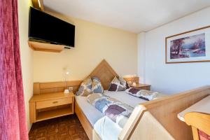 a bedroom with a bed with a tv on the wall at Apt Waldblick in Maranza