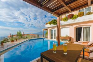 una piscina con dos bebidas en una mesa junto a una casa en Villa Politia, en Atenas