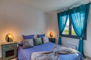 a bedroom with a blue bed with blue curtains and a window at Chambre d’hôtes Béziers in Béziers