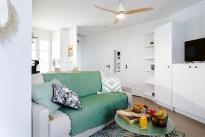 a living room with a green couch and a tv at La Terrasse, Rivedoux Beach House in Rivedoux-Plage