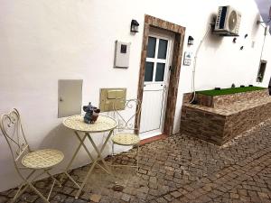 a table and two chairs in front of a door at Casa Gotinha d' Água in Alcaria Ruiva