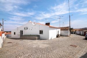 a white building on a cobblestone street at Casa Gotinha d' Água in Alcaria Ruiva