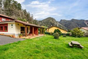 a house in a field with mountains in the background at Apartamentos Les Cuartes in Cangas de Onís