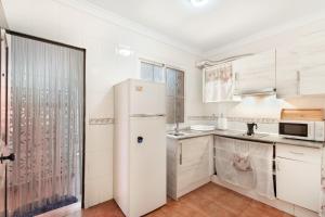 a kitchen with white cabinets and a refrigerator at Duplex Islantilla con piscina in Islantilla
