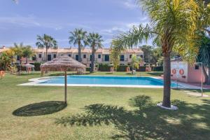 a swimming pool with palm trees and a building at Duplex Islantilla con piscina in Islantilla