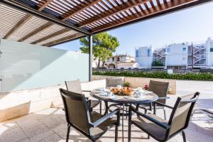 a table and chairs on a patio with a pergola at Duplex La Nau By homevillas360 in Port de Pollensa