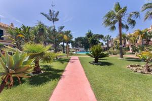 a red pathway in a park with palm trees at Duplex Islantilla con piscina in Islantilla