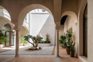 an indoor courtyard with arches and potted plants at Magno Collection Palacio de Becas in Seville +102 photos