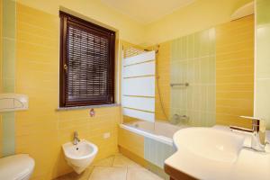 a yellow bathroom with a sink and a toilet at Maison Chateau Chatillon in Châtillon +17 photos