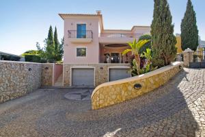 a house with a stone wall and a driveway at Sunshine Villa em Vilamoura in Vilamoura