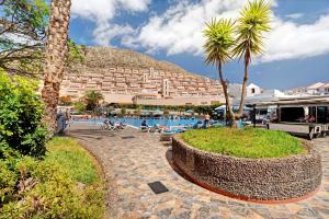 a resort with a pool and palm trees and a building at Castle Harbour in Los Cristianos