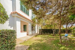 a white house with a yard with chairs and trees at Villa Elfa in Cala en Forcat
