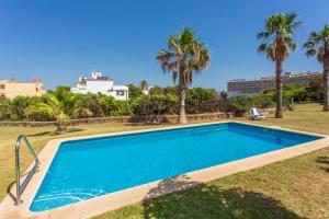 a swimming pool in a yard with palm trees at Villa Elfa in Cala en Forcat