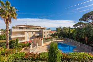 a villa with a swimming pool and palm trees at Petit Paradis à Cavalaire in Cavalaire-sur-Mer