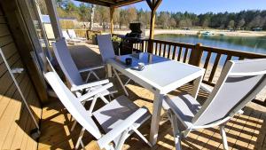 a white table and chairs on a deck with a lake at Sfeervol Veluws Meerhuisje luxe gezinschalet aan het water met opgemaakte bedden en handdoeken in Nunspeet