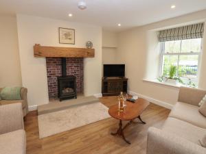 ein Wohnzimmer mit Kamin und Fernseher in der Unterkunft 1 Brookside in Warcop