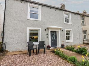 ein Haus mit zwei Stühlen und einem Tisch davor in der Unterkunft 1 Brookside in Warcop