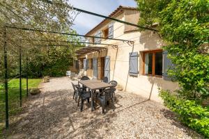 a patio with a table and chairs in front of a house at La Petite Palasse in Le Thor