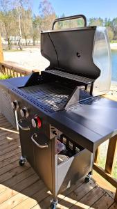 a grill sitting on top of a wooden deck at Sfeervol Veluws Meerhuisje luxe gezinschalet aan het water met opgemaakte bedden en handdoeken in Nunspeet