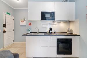 a white kitchen with a sink and a stove at Apartamento Sun7set in Quarteira