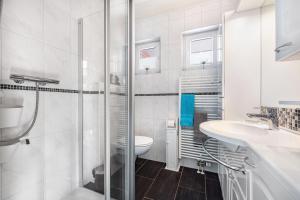 a white bathroom with a toilet and a sink at Ferienhaus Kapitänsstuv in Kaiser Wilhelm Koog +32 photos