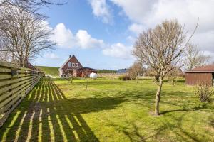 a house in a field with a fence and a tree at Ferienhaus Kapitänsstuv in Kaiser Wilhelm Koog