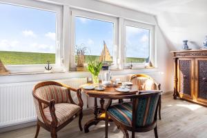 a dining room with a table and chairs and windows at Ferienhaus Kapitänsstuv in Kaiser Wilhelm Koog
