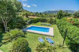 a backyard with a swimming pool and chairs and trees at Sontuiri den Jaume in Pollença