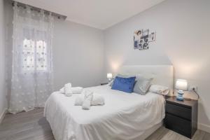 a white bedroom with a large white bed with blue pillows at Grey House in Huelva