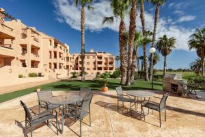 a patio with tables and chairs and palm trees at Golf And Sun in Los Alcázares
