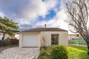 a white house with a garage in a yard at Cap sur la détente - 128 in Pornic