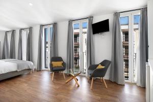 a bedroom with two chairs and a bed and a tv at Casa Milano 2 in Jerez de la Frontera
