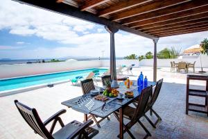 a table with food on it on a patio with a pool at Casa Paula in Yaiza