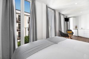 a bedroom with a white bed and large windows at Casa Milano 2 in Jerez de la Frontera