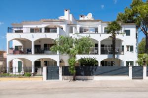 a white house with palm trees in front of it at Apartamento Minerva in Alcudia