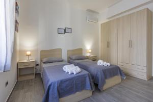 two beds in a room with blue sheets and towels at Casa Gioiosa Holidays in Gioiosa Marea