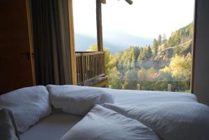 a bed in a room with a large window at Bergchalet h e i m a t in San Martino