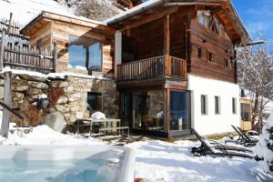 a log house in the snow with a hot tub at Bergchalet h e i m a t in San Martino