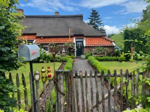 a house with a wooden fence in front of it at Lüttje Reethuus in Südbrookmerland