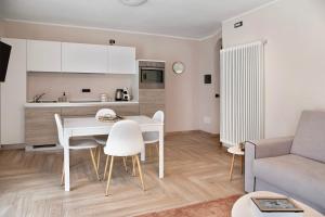 a kitchen and living room with a white table and chairs at La Casetta Chiesa Valmalenco in Chiesa in Valmalenco